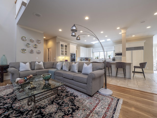 living room with baseboards, recessed lighting, light wood-type flooring, and crown molding