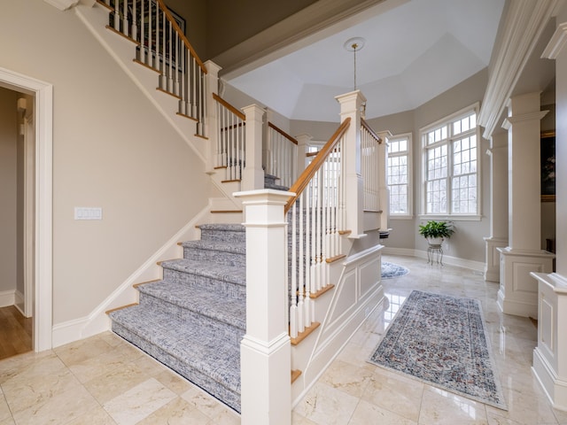 stairway with marble finish floor, decorative columns, and baseboards