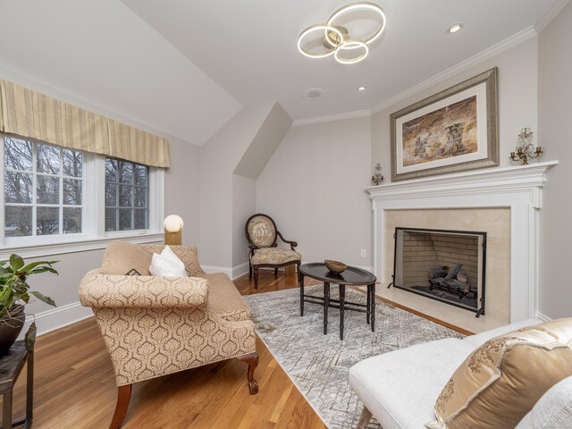 living area with ornamental molding, a tiled fireplace, wood finished floors, and baseboards