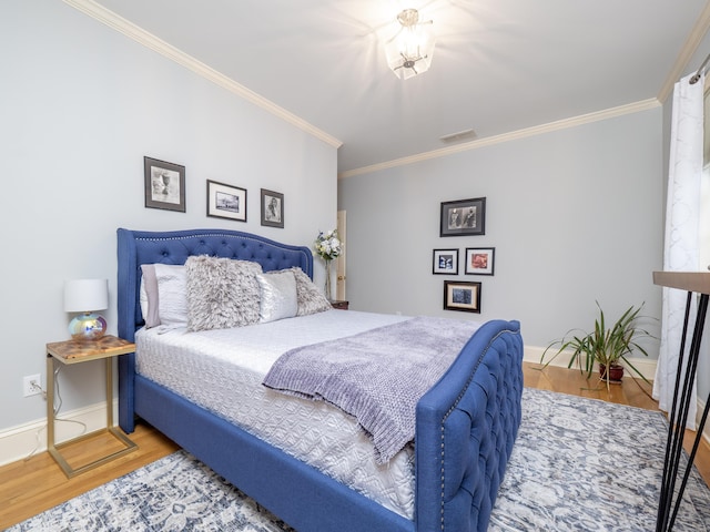 bedroom with visible vents, crown molding, baseboards, and wood finished floors