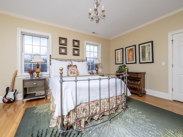 bedroom with visible vents, crown molding, baseboards, and wood finished floors