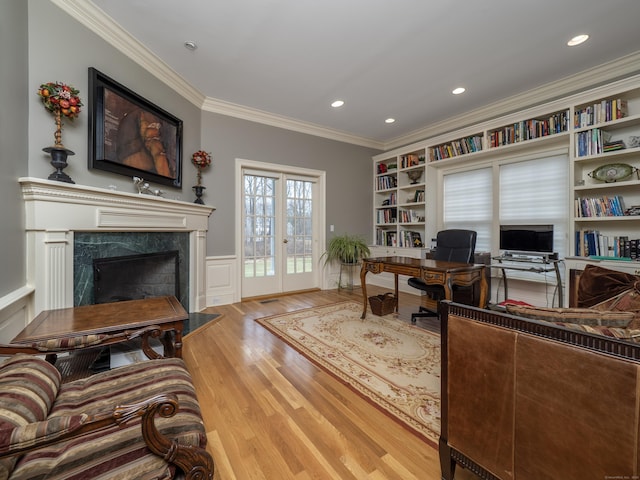 office space featuring recessed lighting, a fireplace, wood finished floors, wainscoting, and crown molding