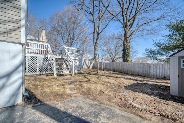 view of yard with an outbuilding, a fenced backyard, a shed, a wooden deck, and stairs