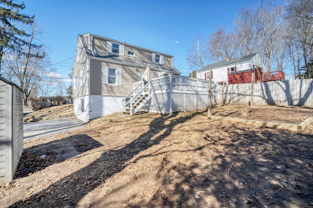 rear view of house with a deck, stairs, and fence