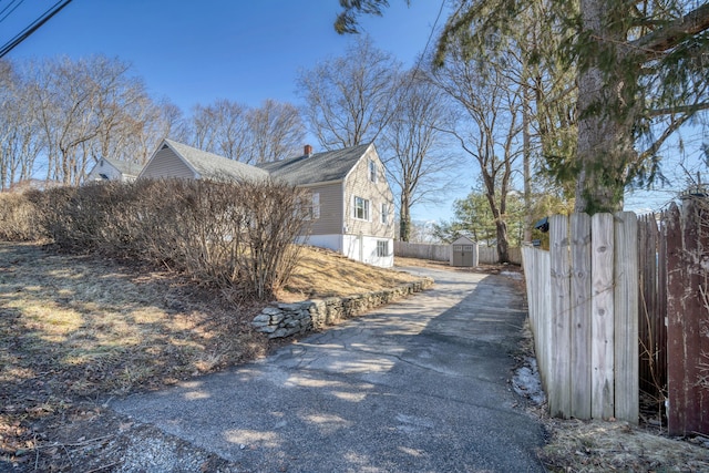 view of side of property with a storage unit, an outbuilding, a chimney, and fence