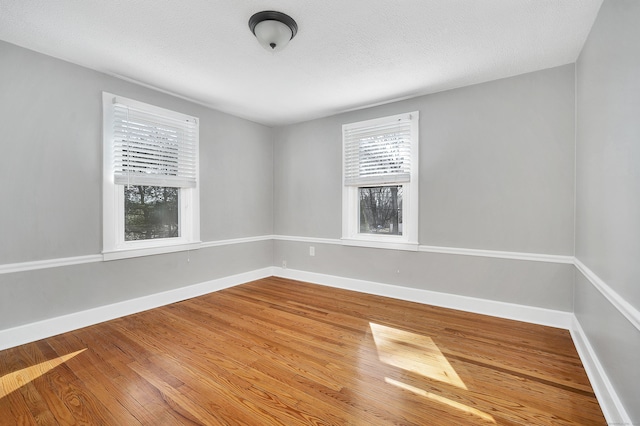 spare room featuring a textured ceiling, baseboards, and wood finished floors