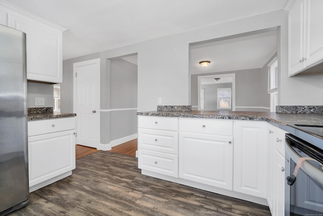 kitchen with dark wood-style floors, white cabinetry, freestanding refrigerator, and dark stone counters