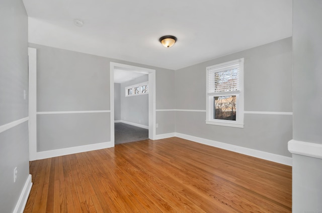 unfurnished room with plenty of natural light, baseboards, and wood-type flooring