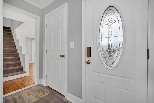 foyer entrance with stairway, baseboards, and wood finished floors