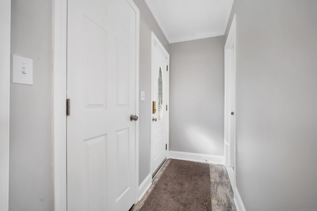 hall with crown molding, baseboards, and dark colored carpet