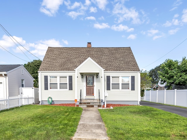 bungalow-style home with roof with shingles, a chimney, a front yard, and fence