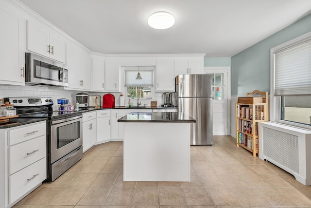 kitchen featuring radiator, dark countertops, stainless steel appliances, and backsplash