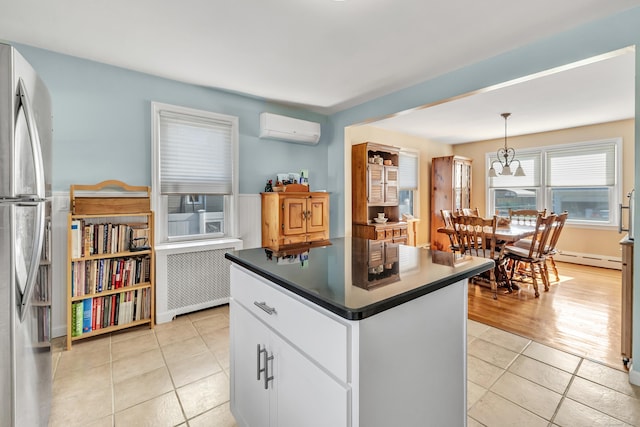 kitchen featuring dark countertops, radiator, freestanding refrigerator, light tile patterned flooring, and a wall mounted air conditioner