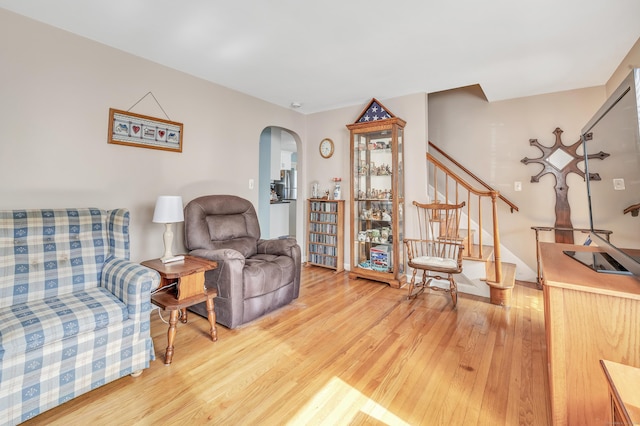 living area with stairs, arched walkways, and wood finished floors