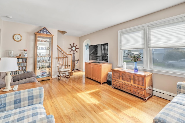 living room featuring light wood finished floors, baseboards, stairway, and baseboard heating