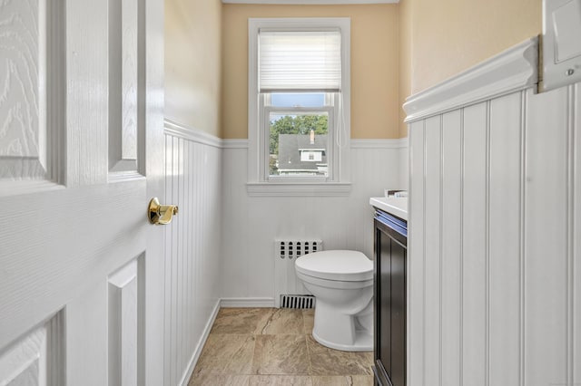 half bath featuring wainscoting, vanity, toilet, and radiator