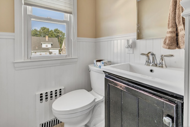 half bathroom with toilet, a wainscoted wall, radiator heating unit, and vanity