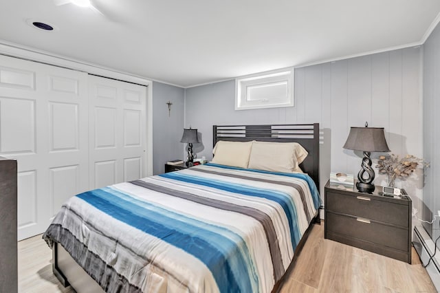 bedroom with ornamental molding, a closet, and light wood finished floors