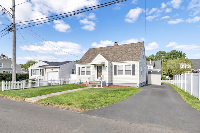 view of front of property with fence private yard, a detached garage, roof with shingles, a residential view, and a front yard