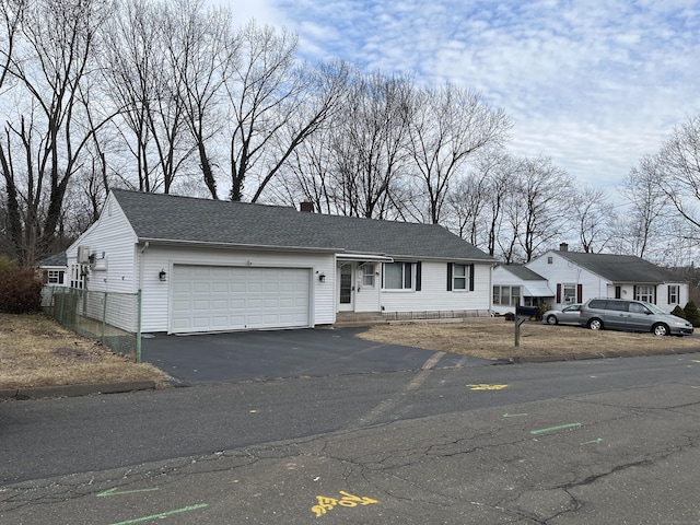 view of front of property featuring roof with shingles, aphalt driveway, a chimney, and an attached garage