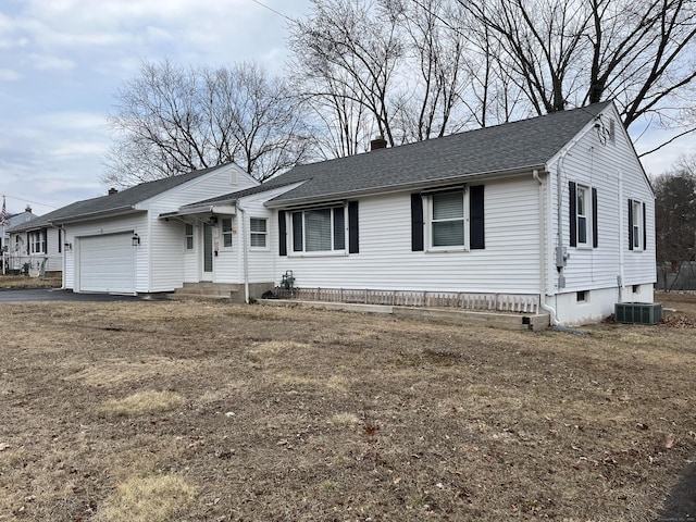 view of front of home featuring a garage, driveway, central AC unit, a chimney, and roof with shingles