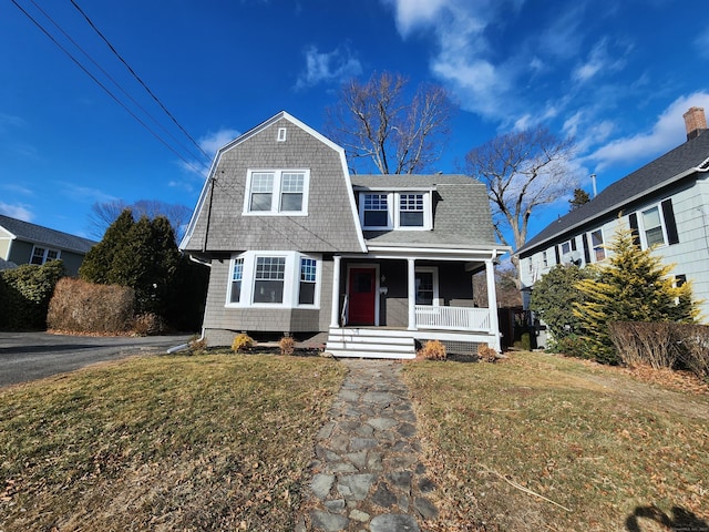 view of front of home featuring a porch, a front yard, a shingled roof, and a gambrel roof