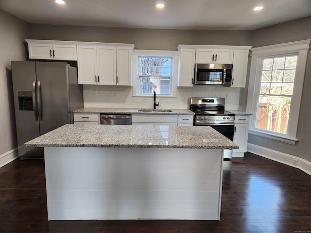 kitchen featuring stainless steel appliances, dark wood-style flooring, a sink, white cabinets, and backsplash