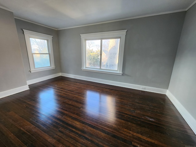 spare room featuring baseboards, ornamental molding, and dark wood-type flooring