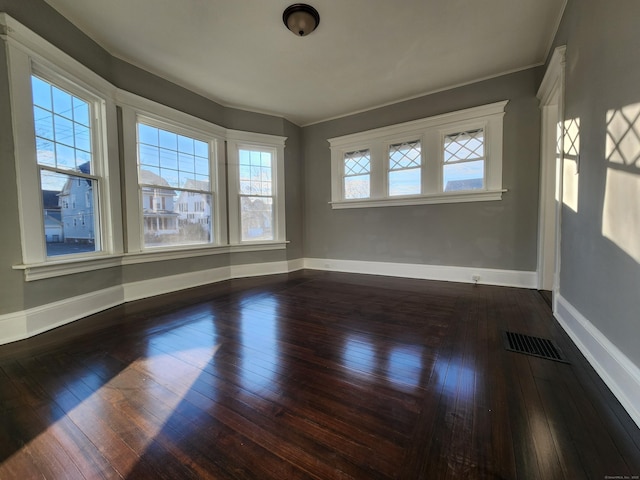 spare room featuring baseboards, visible vents, and dark wood-style flooring