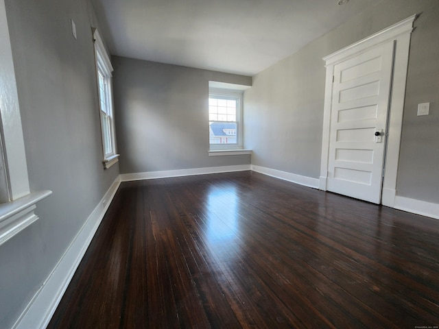 spare room with baseboards and dark wood-style flooring