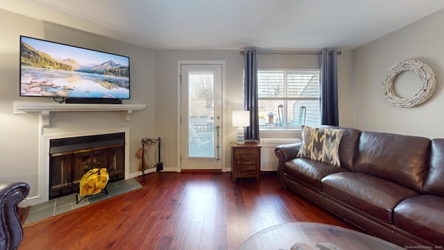 living area with a fireplace with flush hearth, wood finished floors, and baseboards