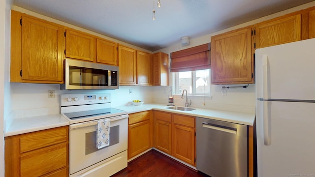 kitchen with a sink, stainless steel appliances, brown cabinets, and light countertops