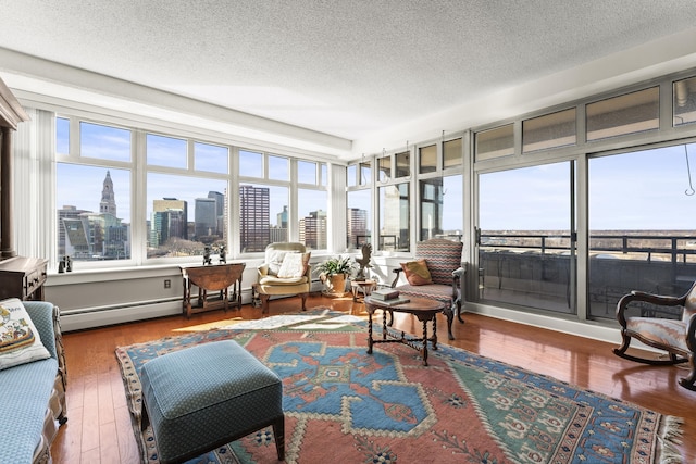 sunroom featuring plenty of natural light, a baseboard radiator, and a view of city