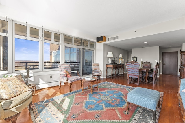 living room featuring baseboards, visible vents, baseboard heating, and wood finished floors