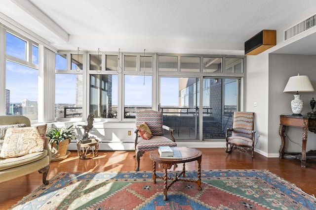 living area featuring a view of city, visible vents, a textured ceiling, wood finished floors, and baseboards