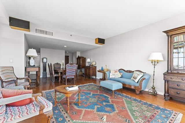 living room featuring baseboards, visible vents, and wood finished floors