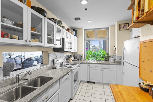 kitchen featuring white appliances, white cabinets, a sink, and light tile patterned flooring