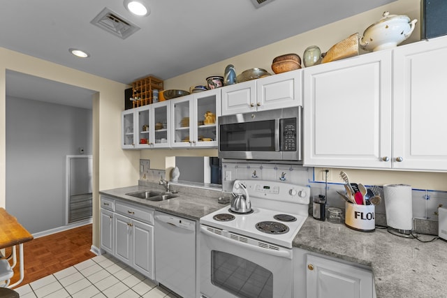 kitchen featuring white appliances, visible vents, white cabinets, glass insert cabinets, and a sink