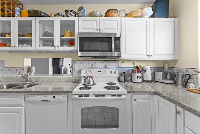 kitchen with white appliances, glass insert cabinets, white cabinets, and a sink