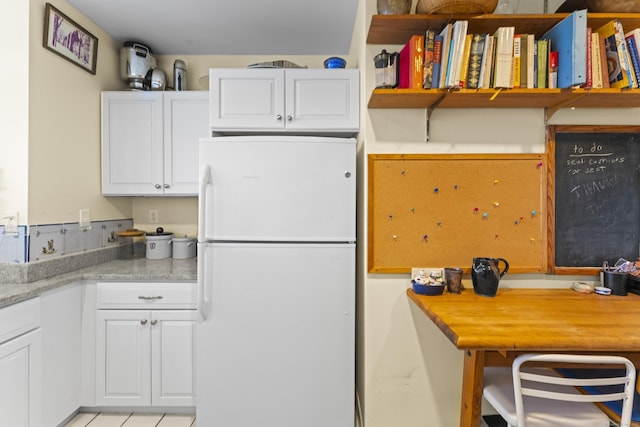 kitchen with open shelves, white cabinetry, light countertops, and freestanding refrigerator