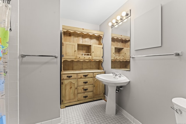 full bath featuring curtained shower, toilet, a sink, baseboards, and tile patterned floors