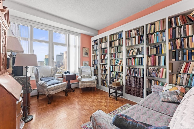 sitting room with wall of books, a baseboard radiator, baseboard heating, and a textured ceiling