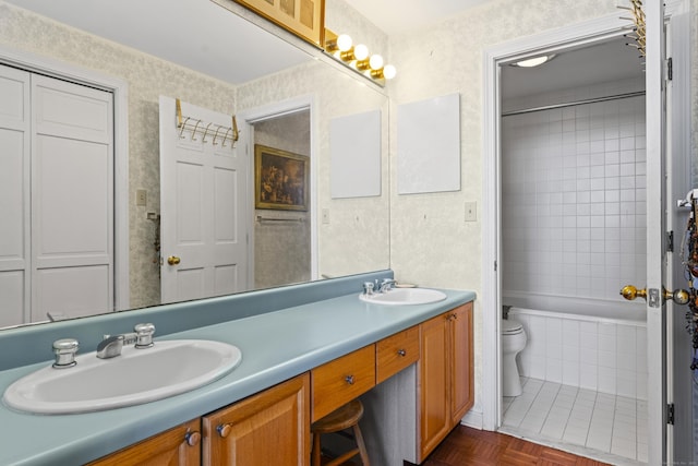 full bath with double vanity, wallpapered walls, toilet, and a sink