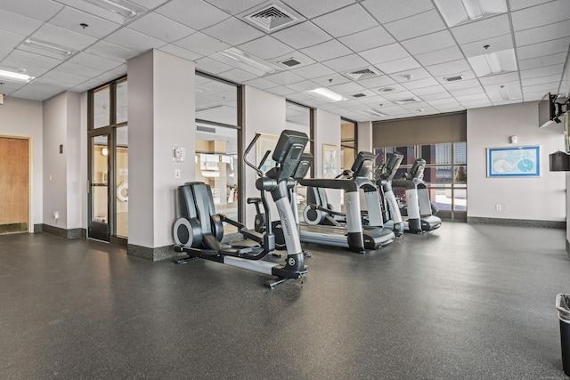 workout area featuring a paneled ceiling, visible vents, and baseboards