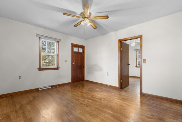 spare room with visible vents, ceiling fan, baseboards, and wood finished floors