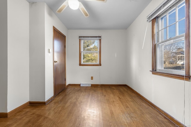 empty room featuring wood-type flooring, visible vents, baseboards, and ceiling fan