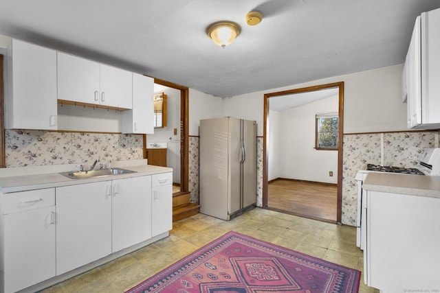 kitchen with light floors, light countertops, white cabinets, a sink, and white appliances