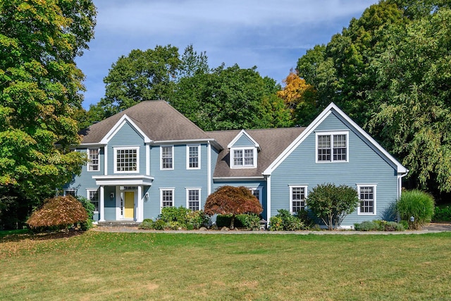 colonial home with a shingled roof and a front yard