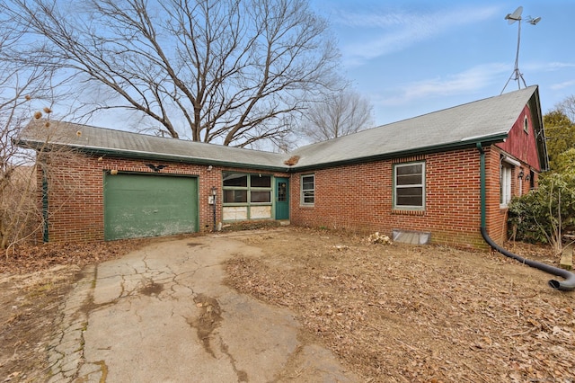 single story home with driveway, brick siding, and an attached garage