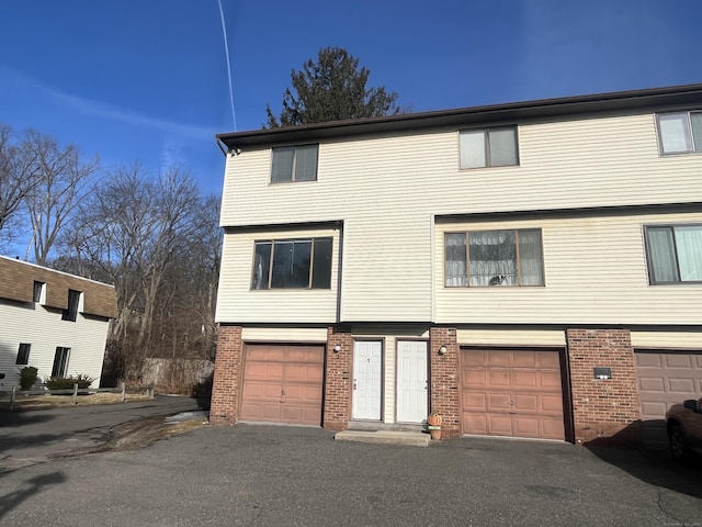 townhome / multi-family property featuring driveway, brick siding, and an attached garage